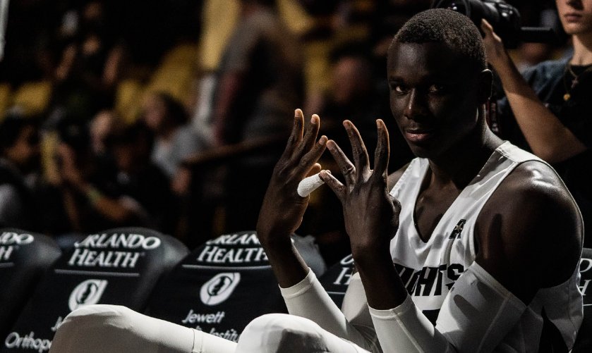 UCF Knights basketball player flashing hands on the bench under arena lights