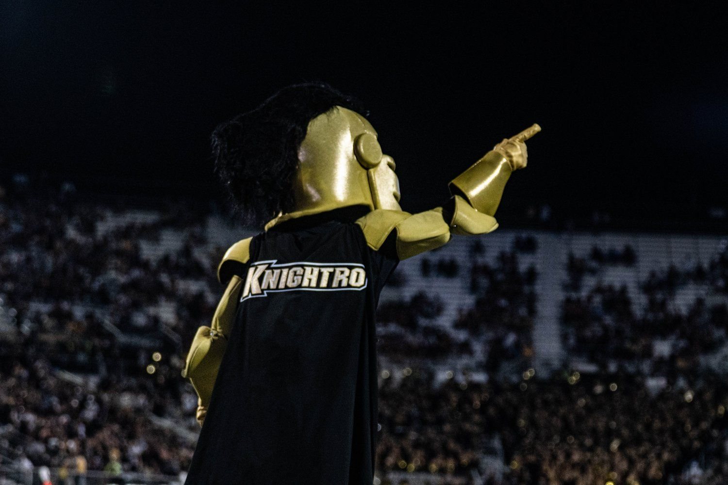 Knightro, the UCF mascot, pointing over the packed Bounce House crowd at night