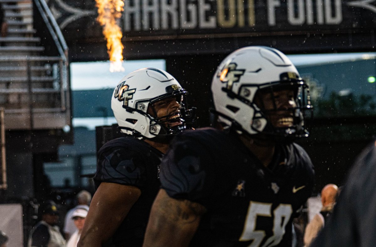 UCF football players entering under the Charge On flame cannons