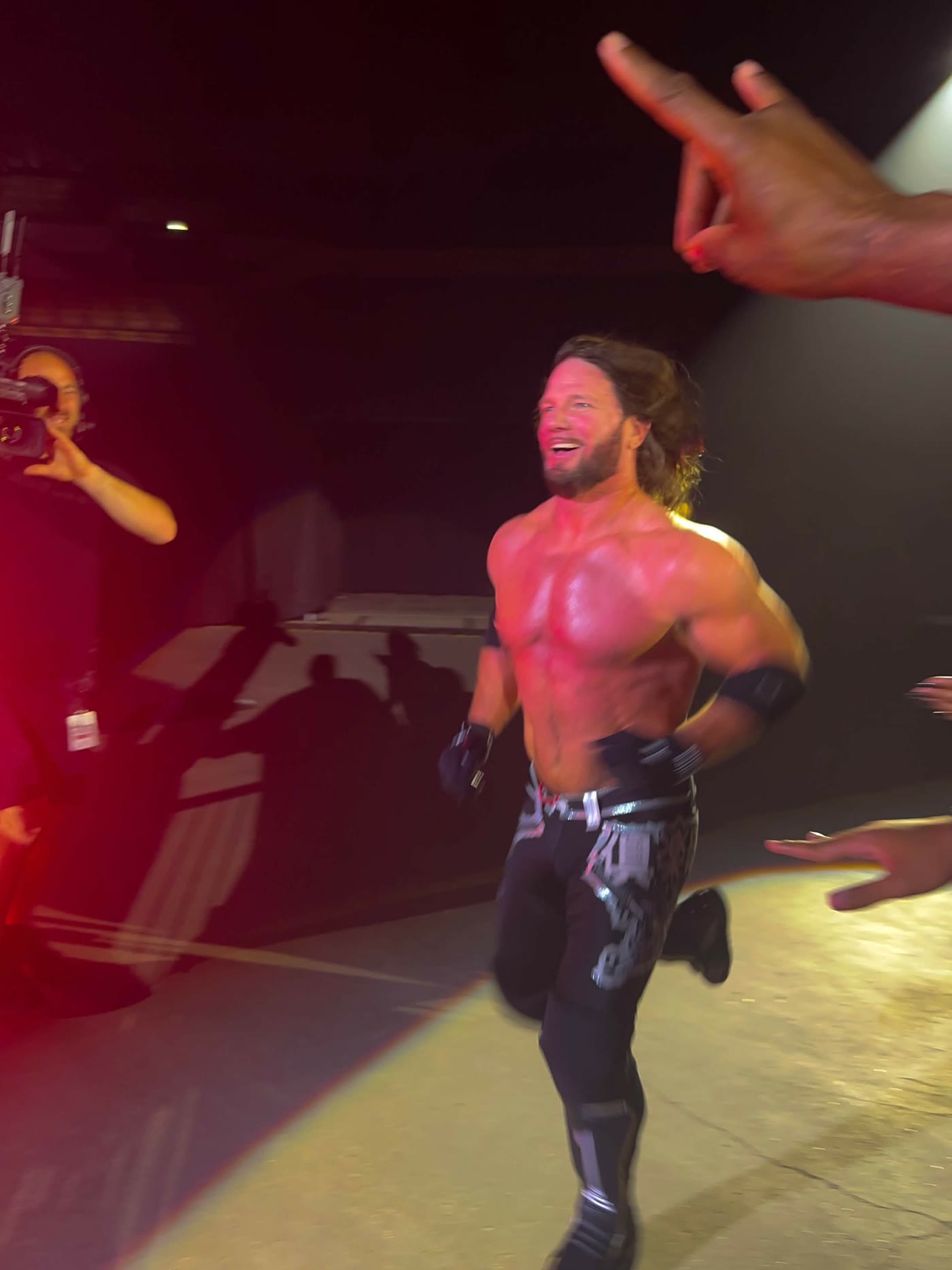 Wrestler walking out through a spotlight in a darkened arena, a fan pointing from the foreground